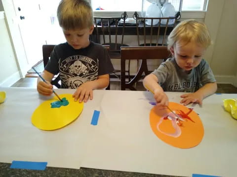 two boys painting on a table