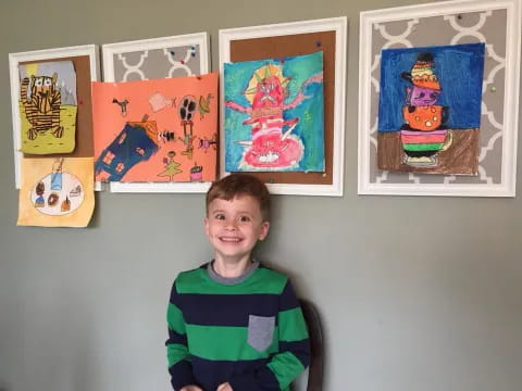 a boy standing in front of a wall with art on it