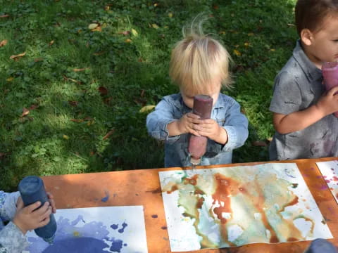 a couple of kids sitting at a table with a painting