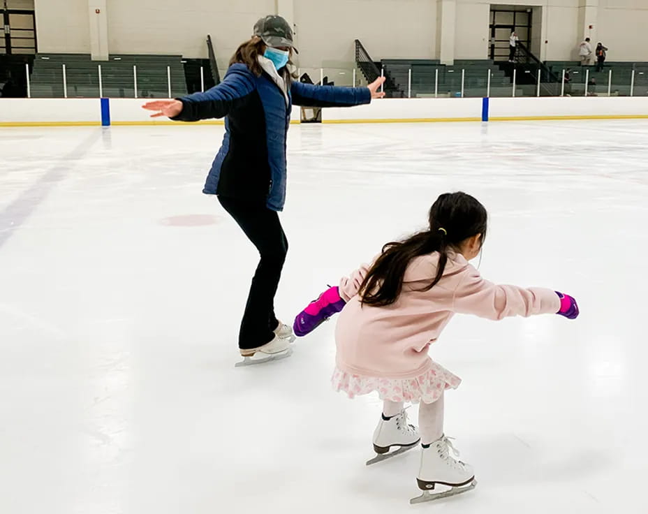 a person and a girl on an ice rink