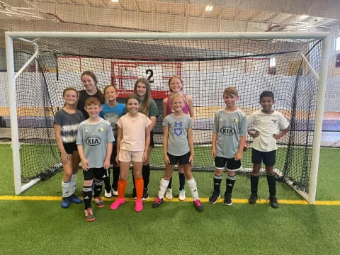 a group of kids posing for a picture in front of a football goal