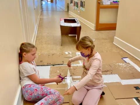 a couple of young girls playing with blocks in a hallway