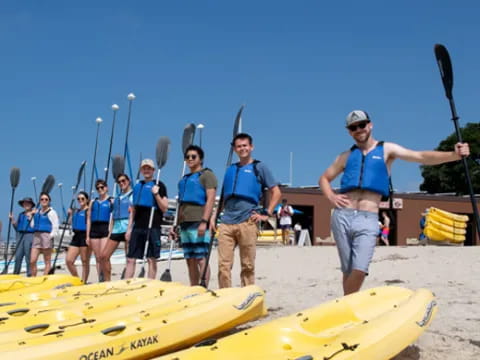 a group of people standing on a beach with paddles