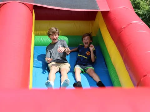 two boys sitting in a large red and yellow slide