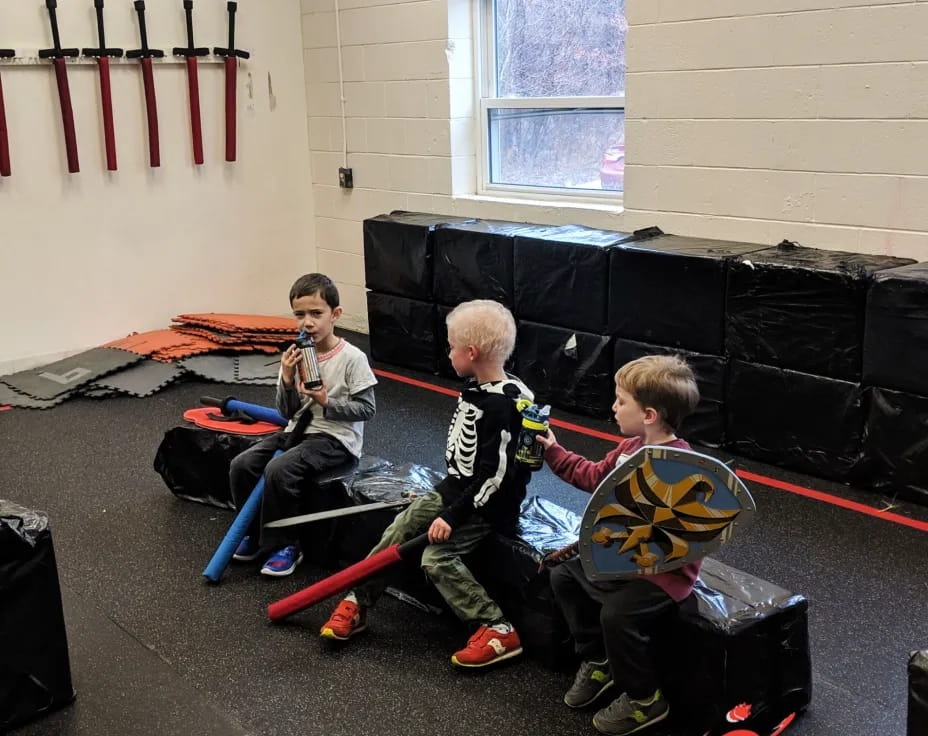 a group of boys sitting on the floor with a black object in front of them