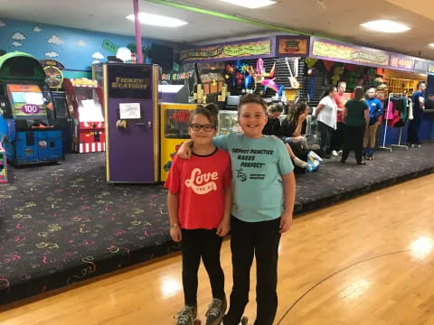 a couple of boys posing for a picture in a bowling alley