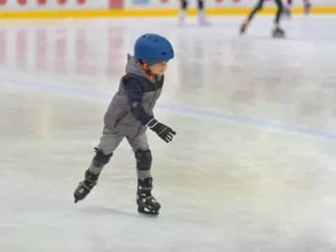a child wearing a helmet and ice skates on a rink