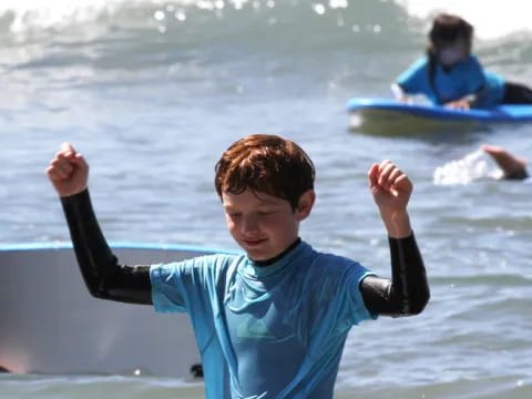 a boy with his arms up in the air in front of a body of water