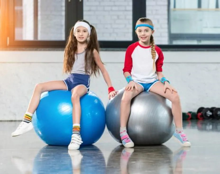 two girls sitting on balls