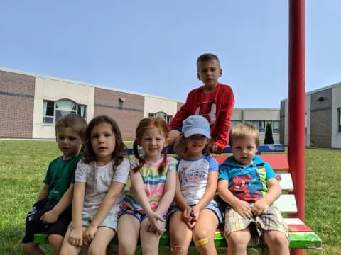 a group of children sitting on a red pole in front of a building