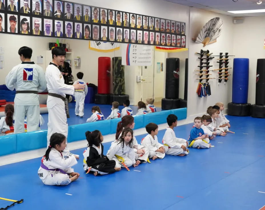 a group of people sitting on the floor in a room with a person standing in the front