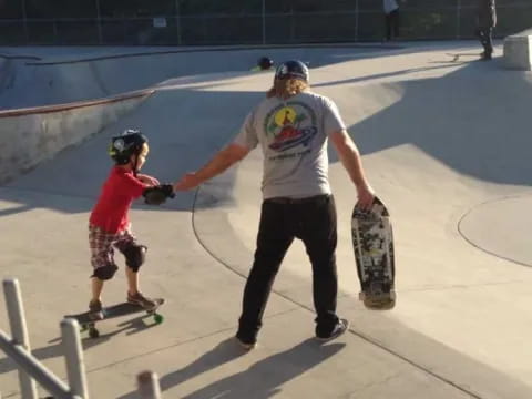 a man and a boy riding skateboards at a skatepark