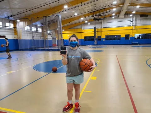 a boy holding a basketball and a basketball in a gym