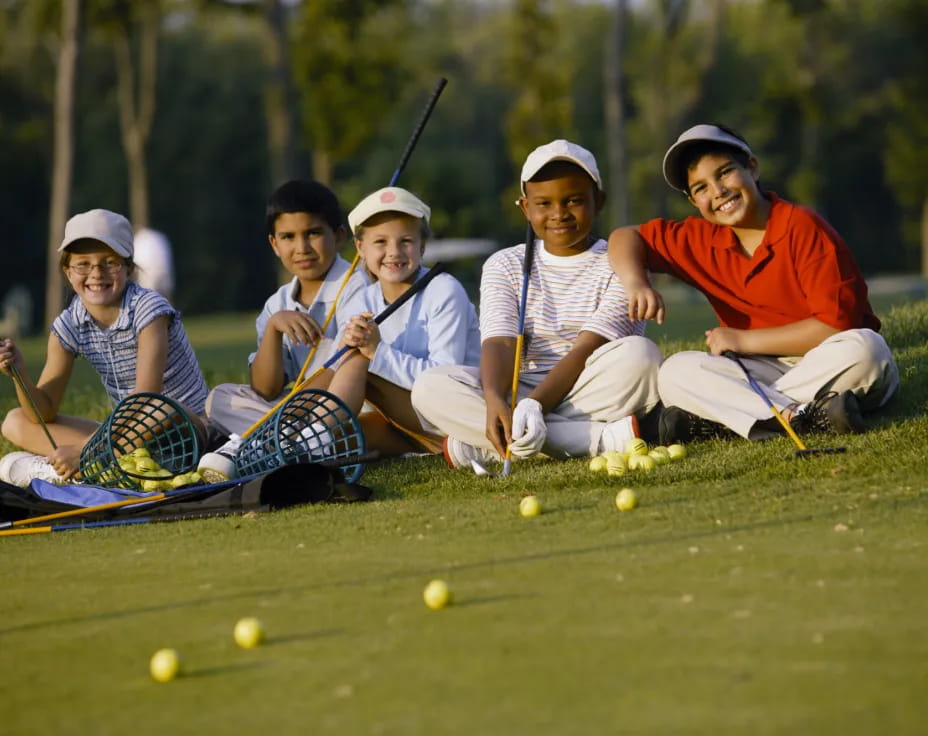a group of people sitting on the grass with golf clubs