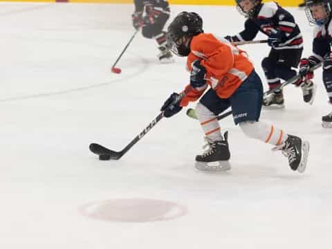 a hockey player in orange and white uniform on ice