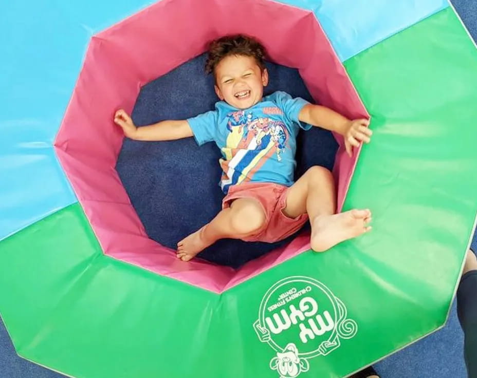 a boy lying on a green and blue slide
