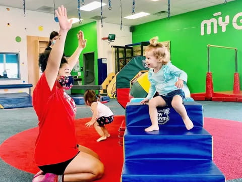 a woman and a group of children on a mat in a gym