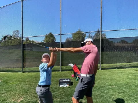 a person and a boy playing golf