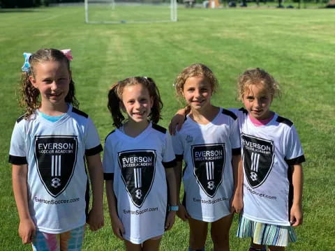 a group of girls in matching t-shirts standing in a grassy field