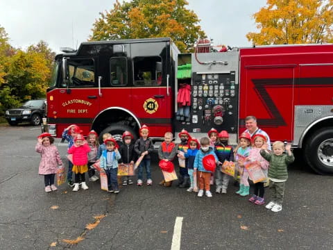 a group of children posing in front of a fire truck