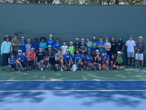 a group of people posing for a photo on a tennis court