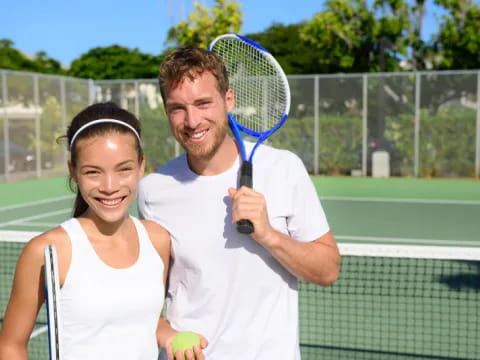 a man and a woman holding tennis rackets
