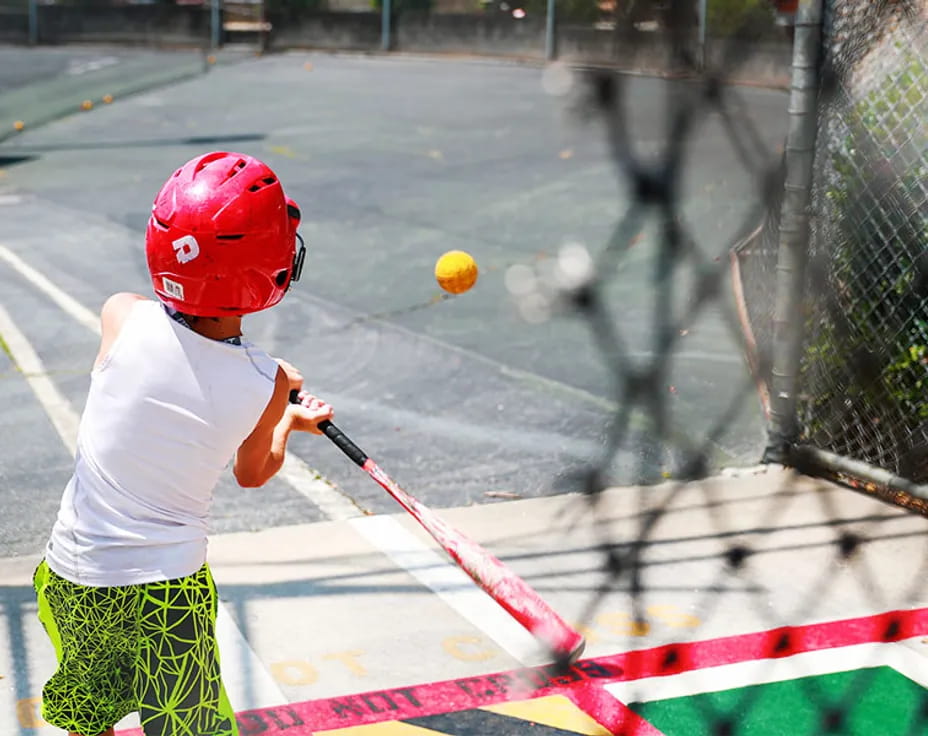 a kid hitting a ball with a baseball bat