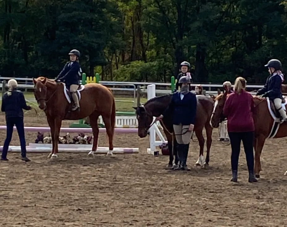 people riding horses in a dirt arena