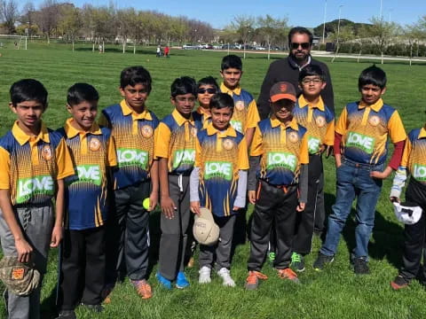 a group of boys in matching yellow shirts standing in a field