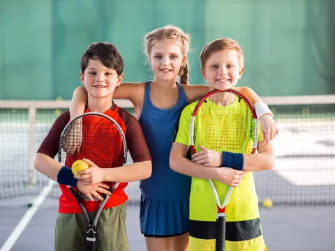 a group of kids holding tennis rackets and balls