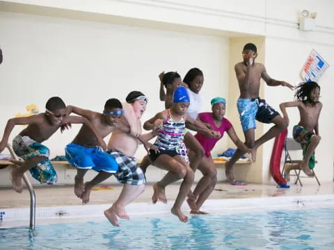 a group of people jumping into a pool