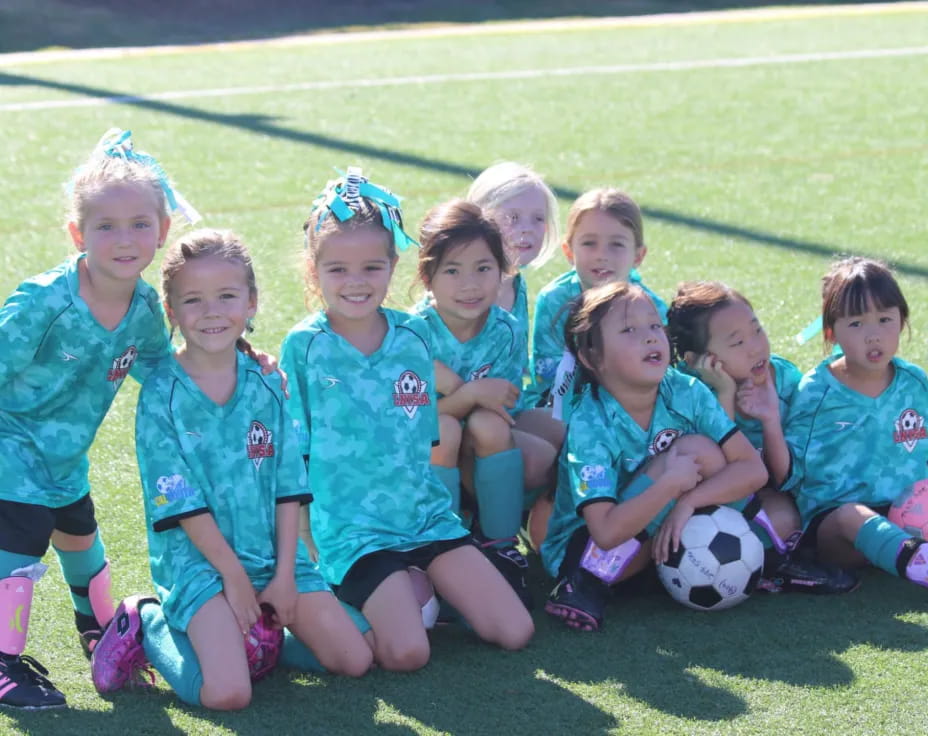 a group of girls posing for a picture with a football ball