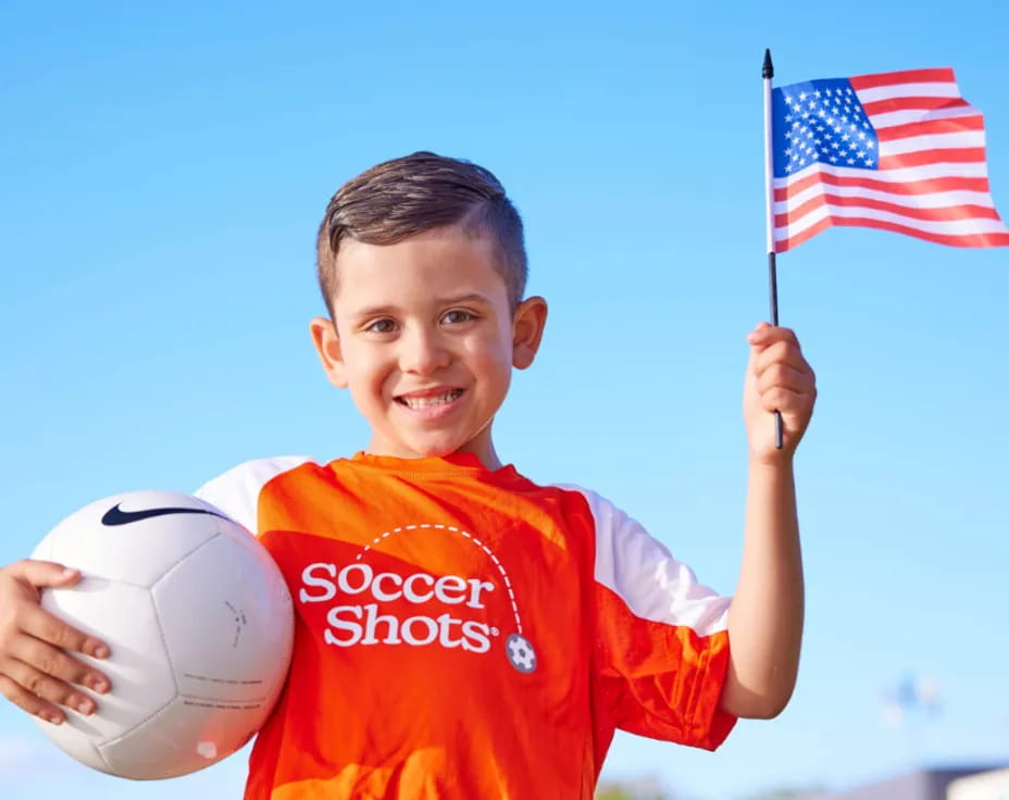 a boy holding a football ball and a flag