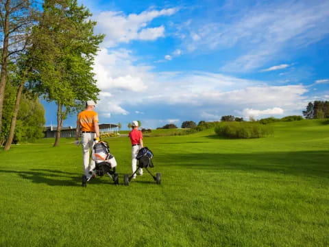 a couple of people walking with strollers on a golf course