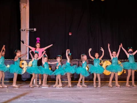 a group of girls in blue and white dresses dancing on a stage