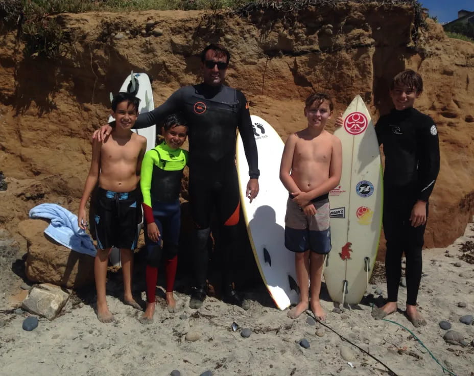 a group of surfers pose with their boards