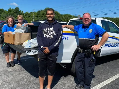 a group of people standing in a parking lot with a police officer