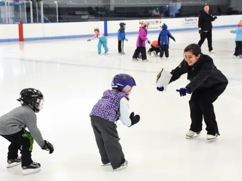 a person and a couple of kids on an ice rink with an audience