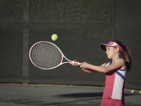 a girl hitting a ball with a tennis racket