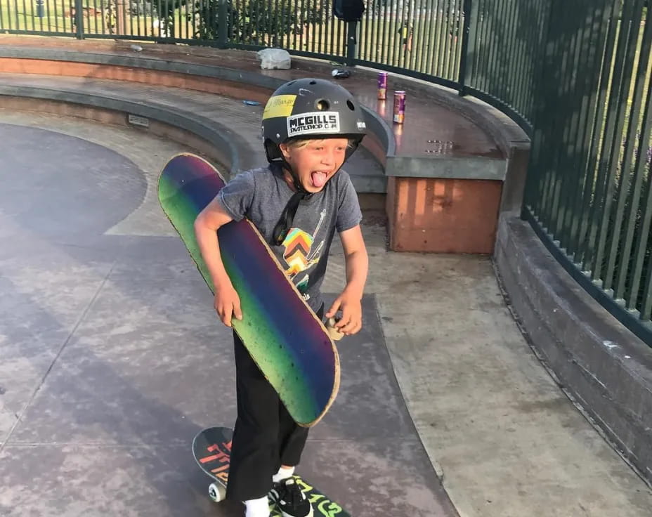 a boy wearing a helmet and holding a skateboard