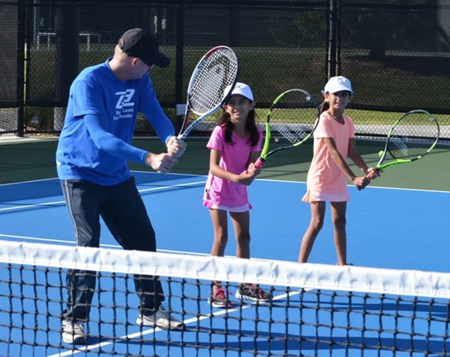 a person and a couple of girls holding tennis rackets