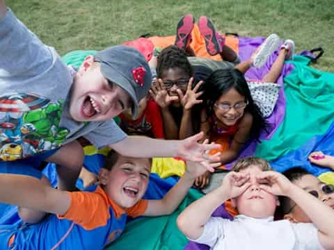 a group of people lying on a blanket on the grass