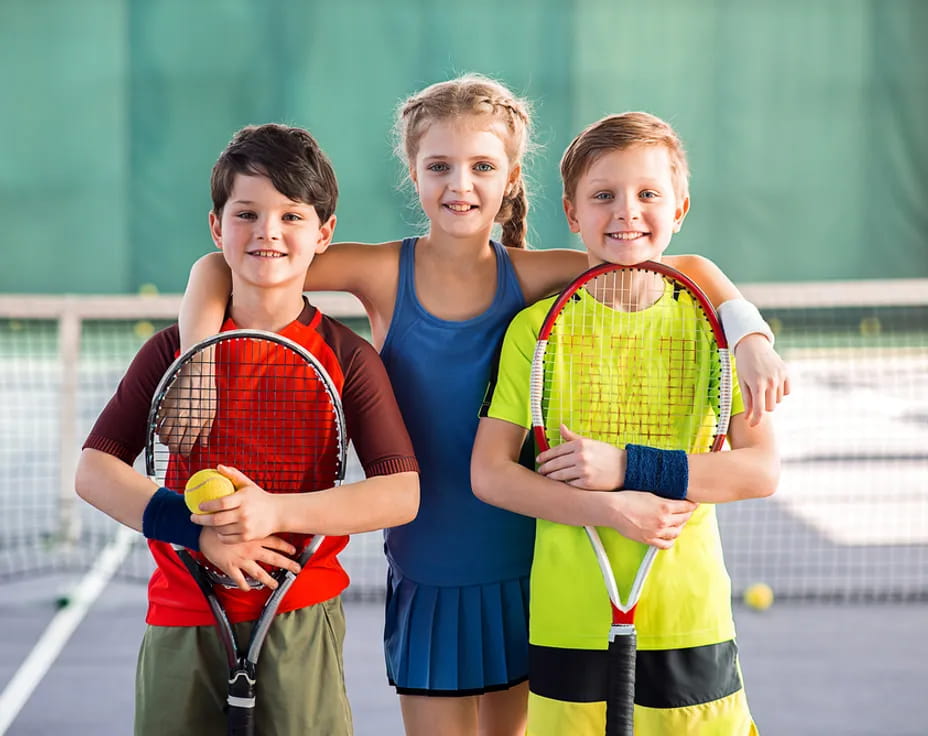a group of kids holding tennis rackets and balls