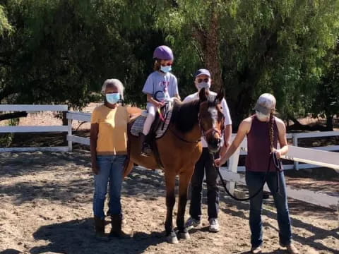 a group of people standing next to a horse with a person on it