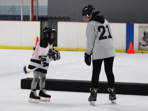 a couple of people wearing helmets and ice skates on an ice rink