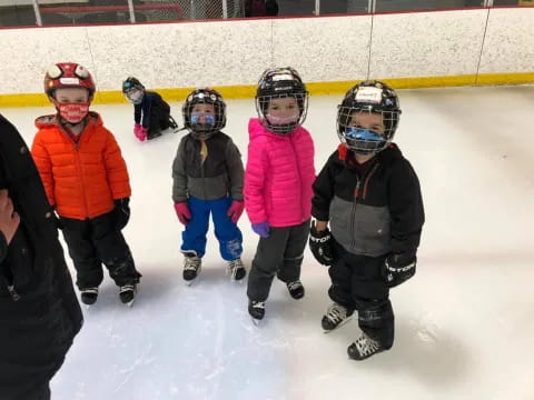 a group of kids wearing helmets and ice skates