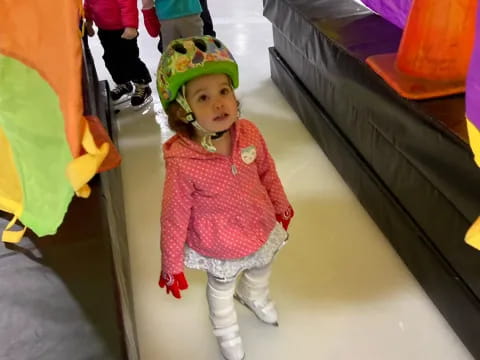 a little girl wearing a helmet and standing in front of a group of children