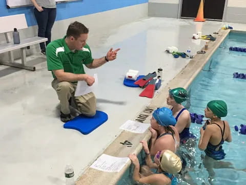 a person sitting on a chair next to a group of people in a pool