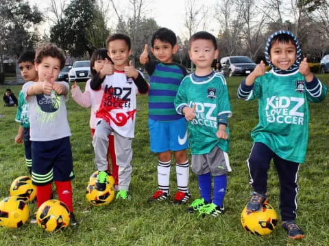 a group of kids stand around some football balls