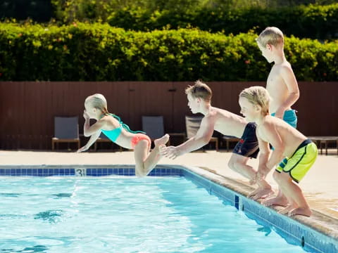 a group of kids jumping into a pool